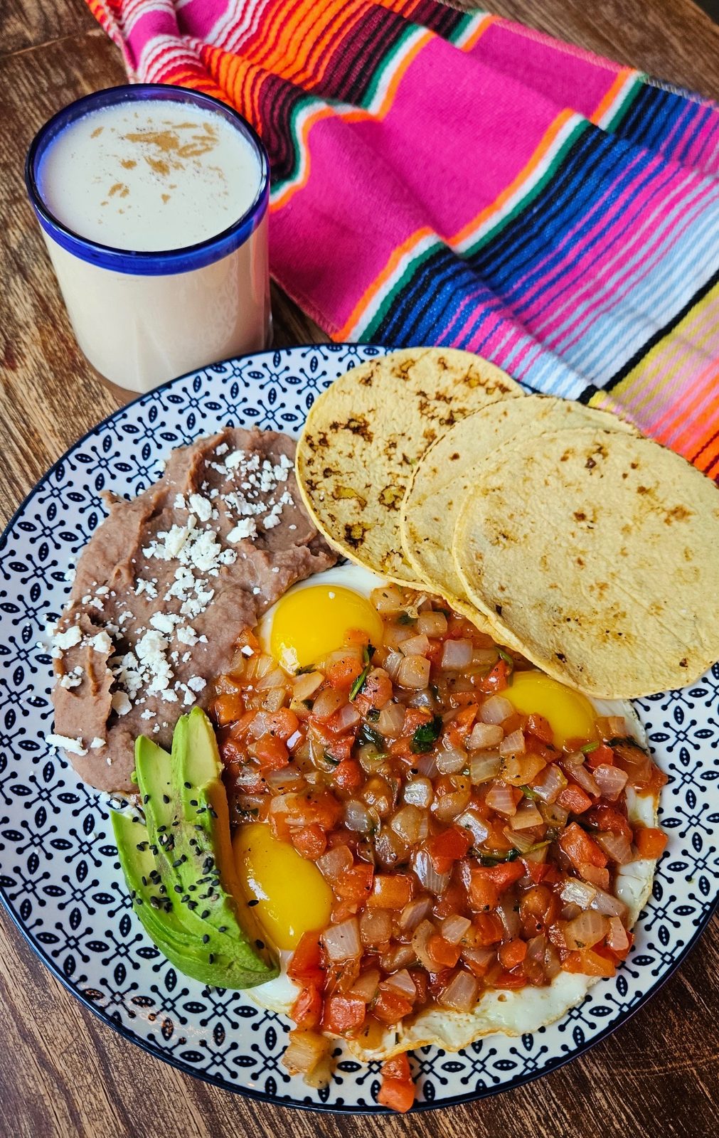 Huevos a la Mexicana, three fried eggs with homemade Mexican sauce, beans and avocado